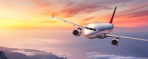Airplane flies over the sea at sunset.